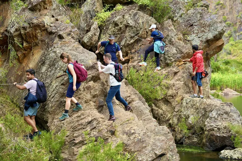 Social Hikes Australia group scrambling over rocks beside the river in Werribee Gorge